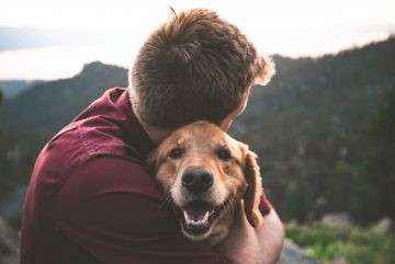 Homem e cachorro abraçados